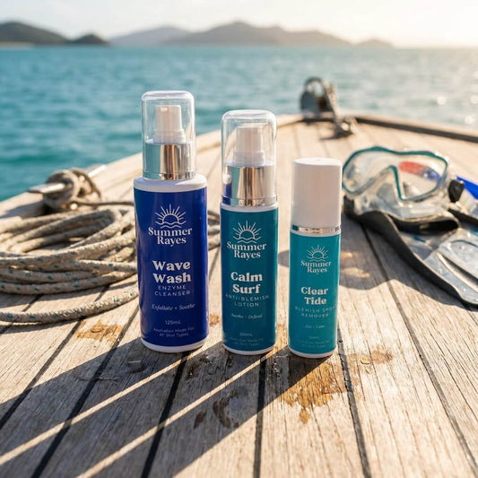 Three Summer Rays teen boys skincare products standing on a wooden boat deck with ocean water and diving gear in the background.