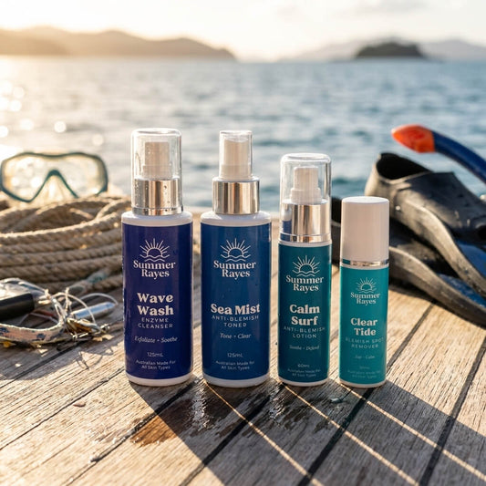 Four Summer Rayes skincare bottles arranged on a wooden dock by the ocean, with snorkeling gear and a swim cap in the background.