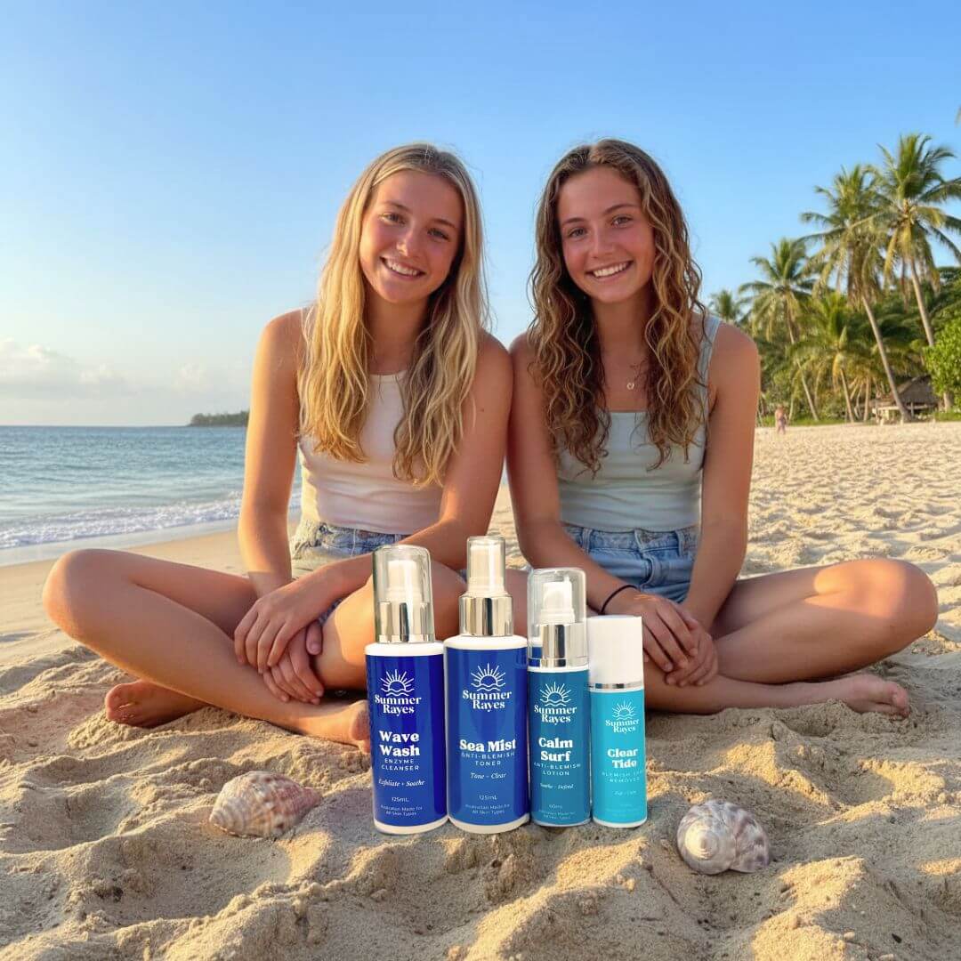 Two teenagers sitting on a beach with bottles of Summer Rayes skincare products.