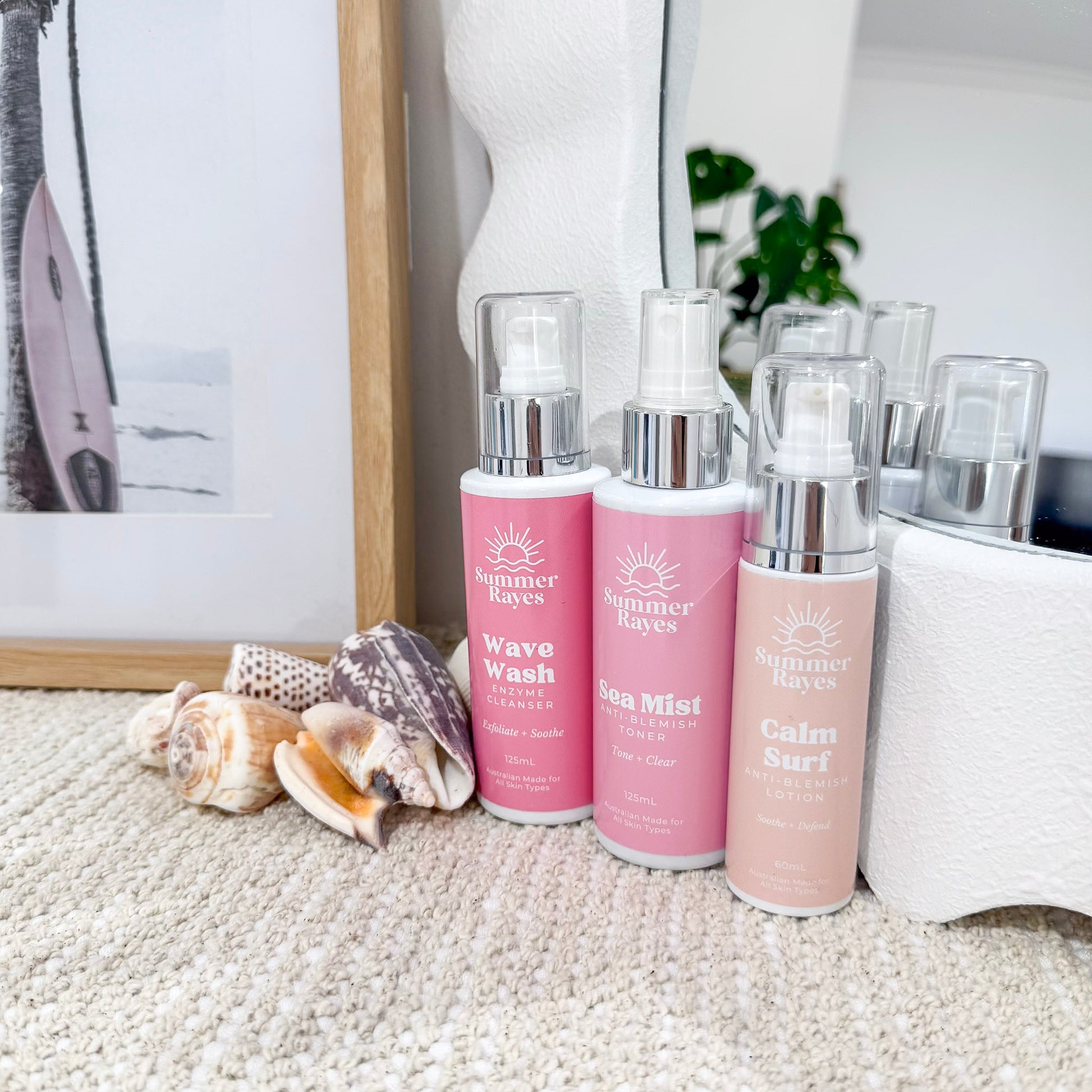Three pink bottles with silver caps labeled 'Summer rayes' on a textured surface.
