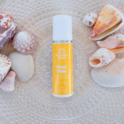 Bottle of 'Clear Tide' teen skincare product by Summer rayes on a textured surface with seashells.
