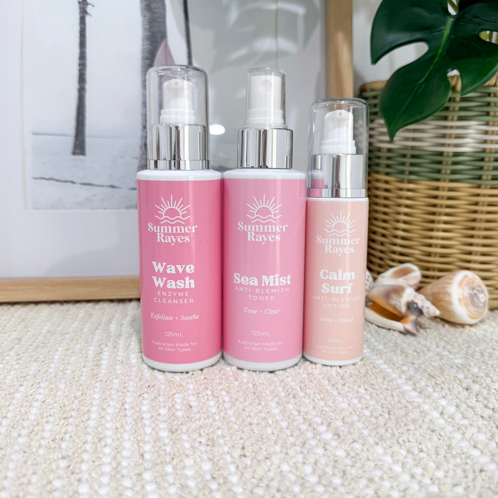 Three pink bottles with silver caps labeled 'Summer Rayes' on a textured surface.
