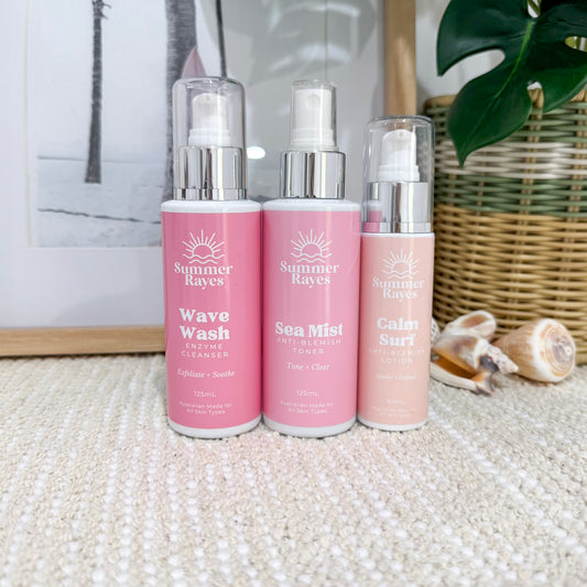 Three pink bottles with silver caps labeled 'Summer Rayes' on a textured surface.