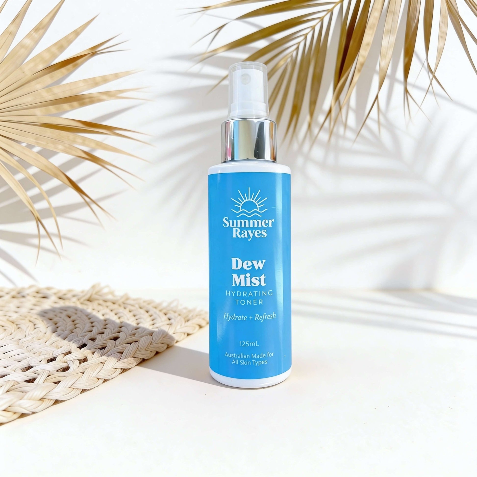 Summer Rayes Dew Mist bottle on a white surface with palm leaves in the background