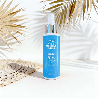 Summer Rayes Dew Mist bottle on a white surface with palm leaves in the background