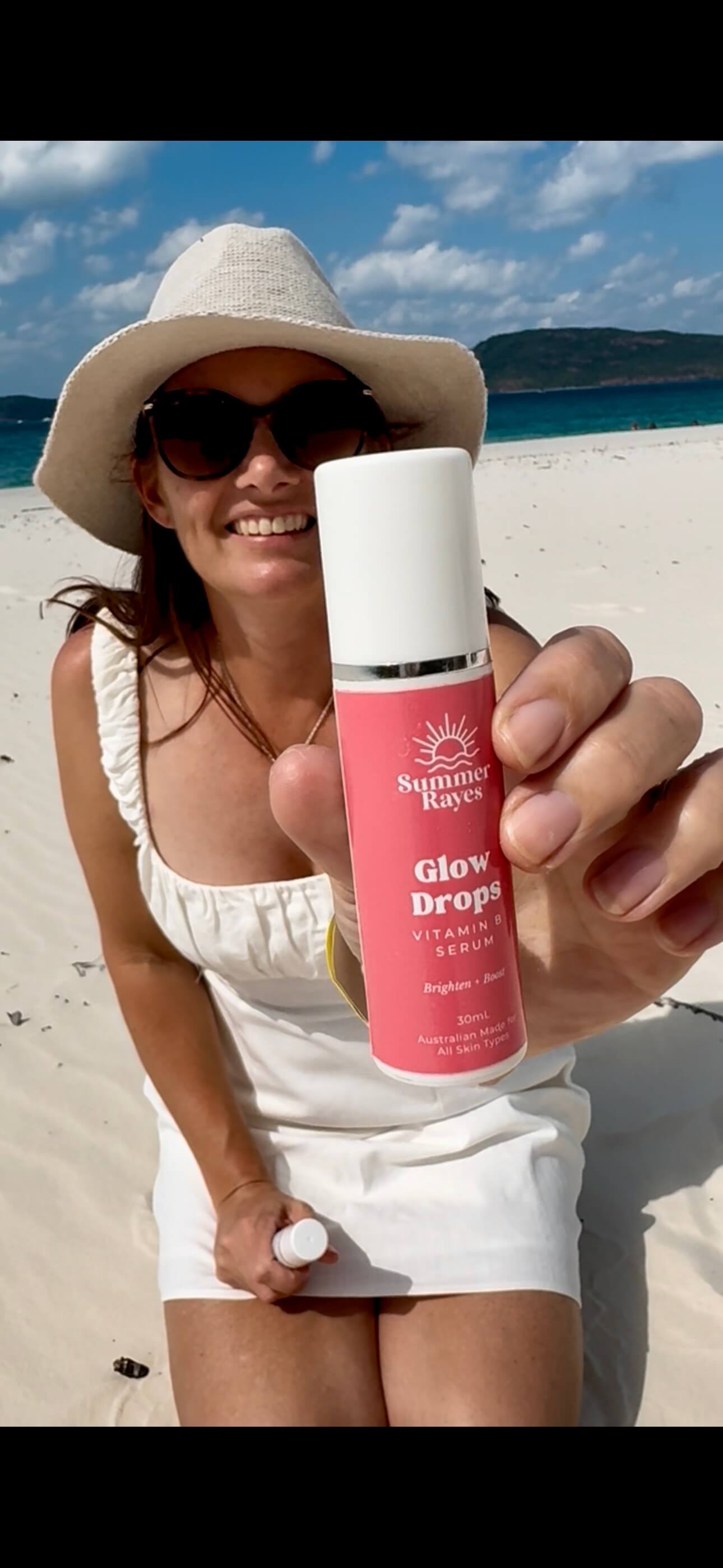 A mum of teens on the beach holding out a teen skincare product from Summer Rayes