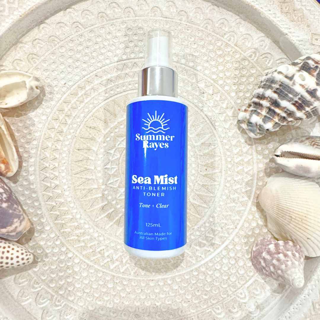 Summer Rayes Teen skincare for boys & girls Sea Mist toner bottle surrounded by seashells on a textured surface