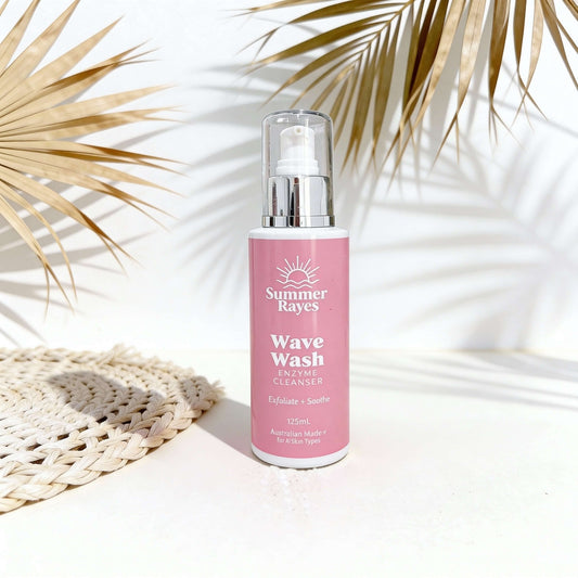 Pink bottle of Summer Rayes Wave Wash with palm leaves in the background