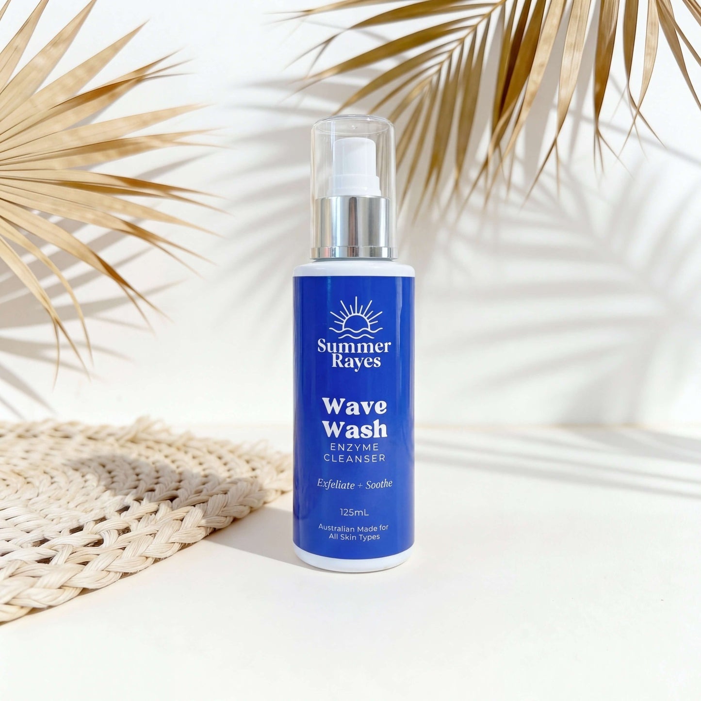 Blue bottle of Summer Rayes Wave Wash on a white background with palm leaves.